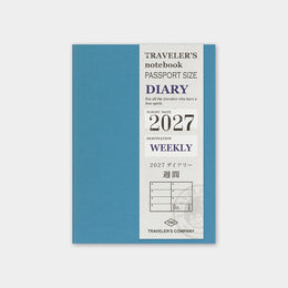A 2027 weekly traveler's notebook by Traveler's Company, featuring a slate blue cover with a white vertical panel detailing the text and year.